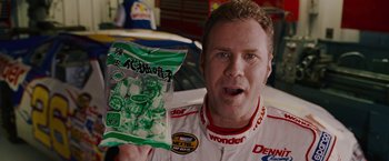 Movie still from “Talladega Nights: The Ballad of Ricky Bobby” (2006), directed by Adam McKay – A man holding a bag of chips in front of his face; Close Up shot, Over the shoulder angle