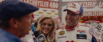 Movie still from “Talladega Nights: The Ballad of Ricky Bobby” (2006), directed by Adam McKay – A couple of people that are standing up in a room; Close Up shot, Over the shoulder angle