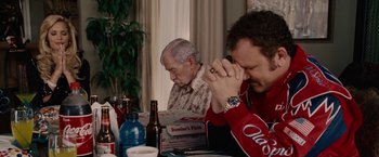 Movie still from “Talladega Nights: The Ballad of Ricky Bobby” (2006), directed by Adam McKay – Two men sitting at a dinner table eating pizza; Medium shot, High angle