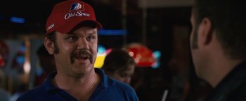 Movie still from “Talladega Nights: The Ballad of Ricky Bobby” (2006), directed by Adam McKay – A man with a beard wearing a red and blue hat; Close Up shot, Over the shoulder angle