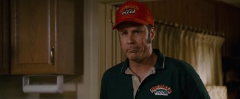 Movie still from “Talladega Nights: The Ballad of Ricky Bobby” (2006), directed by Adam McKay – A man wearing a red hat and a green shirt; Close Up shot, Over the shoulder angle