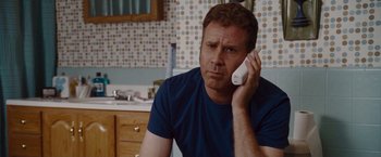Movie still from “Talladega Nights: The Ballad of Ricky Bobby” (2006), directed by Adam McKay – A man sitting in a bathroom talking on a phone; Close Up shot, High angle