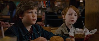 Movie still from “Talladega Nights: The Ballad of Ricky Bobby” (2006), directed by Adam McKay – Two young boys sitting at a table in front of a bun; Close Up shot, Over the shoulder angle
