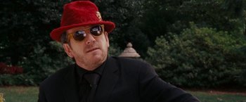 Movie still from “Talladega Nights: The Ballad of Ricky Bobby” (2006), directed by Adam McKay – A man in a suit and a red hat; Close Up shot, Low angle