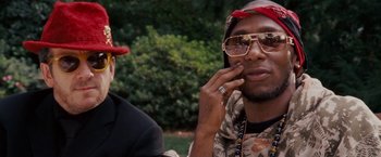 Movie still from “Talladega Nights: The Ballad of Ricky Bobby” (2006), directed by Adam McKay – A man with a red hat and sunglasses and a man with a red hat; Close Up shot, Low angle