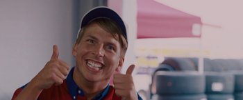 Movie still from “Talladega Nights: The Ballad of Ricky Bobby” (2006), directed by Adam McKay – A man giving a thumbs up while wearing a baseball cap; Close Up shot, Low angle