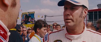 Movie still from “Talladega Nights: The Ballad of Ricky Bobby” (2006), directed by Adam McKay – A group of men standing next to each other on a race track; Close Up shot, Over the shoulder angle