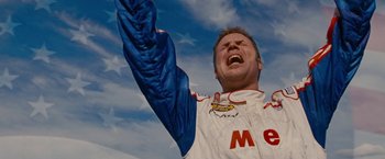 Movie still from “Talladega Nights: The Ballad of Ricky Bobby” (2006), directed by Adam McKay – A man in a racing suit is raising his arm in the air; Close Up shot, Low angle