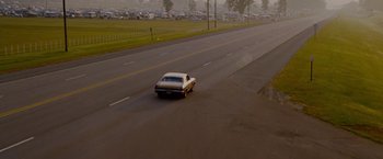 Movie still from “Talladega Nights: The Ballad of Ricky Bobby” (2006), directed by Adam McKay – A car driving down a street near a parking lot; Extreme Wide shot, High angle