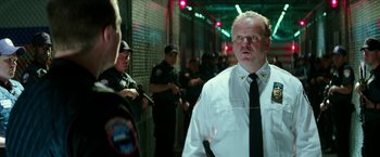 Movie still from “Teenage Mutant Ninja Turtles: Out of the Shadows” (2016), directed by Dave Green – A man in a white shirt and tie standing next to a group of people; Close Up shot, Over the shoulder angle