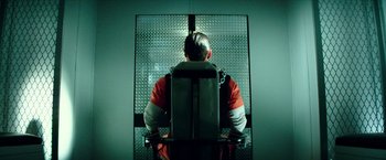 Movie still from “Teenage Mutant Ninja Turtles: Out of the Shadows” (2016), directed by Dave Green – A man in orange and white is sitting in a jail cell; Wide shot, High angle
