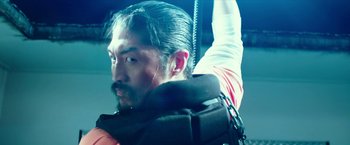 Movie still from “Teenage Mutant Ninja Turtles: Out of the Shadows” (2016), directed by Dave Green – A man with long black hair and a black backpack; Close Up shot, Low angle