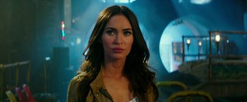 Movie still from “Teenage Mutant Ninja Turtles: Out of the Shadows” (2016), directed by Dave Green – A beautiful woman with long brown hair wearing a tan jacket; Close Up shot, Over the shoulder angle