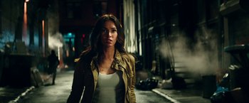 Movie still from “Teenage Mutant Ninja Turtles: Out of the Shadows” (2016), directed by Dave Green – A woman standing on a city street at night; Close Up shot, Over the shoulder angle