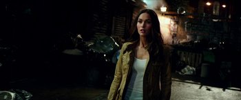 Movie still from “Teenage Mutant Ninja Turtles: Out of the Shadows” (2016), directed by Dave Green – A beautiful woman standing next to a pile of garbage; Medium shot, Over the shoulder angle