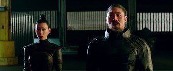 Movie still from “Teenage Mutant Ninja Turtles: Out of the Shadows” (2016), directed by Dave Green – A man and a woman standing next to each other in front of a building; Medium shot, Low angle