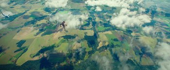Movie still from “Teenage Mutant Ninja Turtles: Out of the Shadows” (2016), directed by Dave Green – A person is parachuting in the air over a field; Extreme Wide shot, Overhead angle