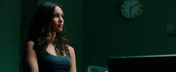 Movie still from “Teenage Mutant Ninja Turtles: Out of the Shadows” (2016), directed by Dave Green – A woman sitting in front of a clock in front of a green wall; Close Up shot, Over the shoulder angle