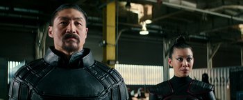 Movie still from “Teenage Mutant Ninja Turtles: Out of the Shadows” (2016), directed by Dave Green – A man in a black suit and a man in a red suit; Close Up shot, Over the shoulder angle