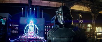 Movie still from “Teenage Mutant Ninja Turtles: Out of the Shadows” (2016), directed by Dave Green – A man in a black suit with a metal mask on his face; Medium shot, Over the shoulder angle