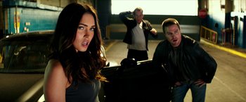 Movie still from “Teenage Mutant Ninja Turtles: Out of the Shadows” (2016), directed by Dave Green – Two men and a woman standing next to each other in a parking lot; Medium shot, Over the shoulder angle