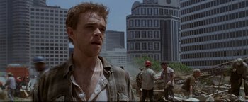 Movie still from “Terminator 3: Rise of the Machines” (2003), directed by Jonathan Mostow – A group of men standing next to each other near a building; Close Up shot, Low angle