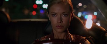 Movie still from “Terminator 3: Rise of the Machines” (2003), directed by Jonathan Mostow – A beautiful woman sitting in a car in front of some lights; Close Up shot, Over the shoulder angle