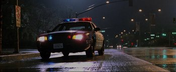 Movie still from “Terminator 3: Rise of the Machines” (2003), directed by Jonathan Mostow – A police car driving down a street at night; Wide shot, Low angle