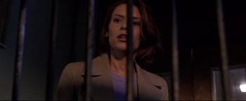 Movie still from “Terminator 3: Rise of the Machines” (2003), directed by Jonathan Mostow – A woman in a brown jacket behind a metal fence; Close Up shot, Low angle