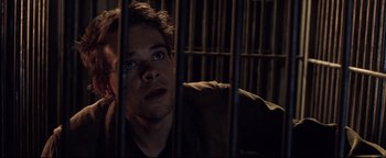 Movie still from “Terminator 3: Rise of the Machines” (2003), directed by Jonathan Mostow – A man sitting behind bars in a jail cell; Close Up shot, High angle