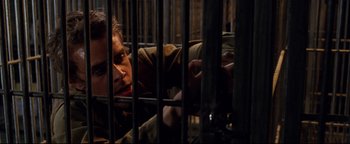 Movie still from “Terminator 3: Rise of the Machines” (2003), directed by Jonathan Mostow – A man in a jail cell looking through the bars; Close Up shot, High angle