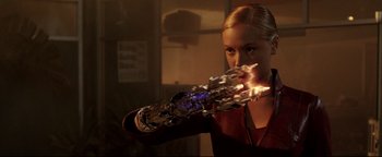 Movie still from “Terminator 3: Rise of the Machines” (2003), directed by Jonathan Mostow – A woman is holding a futuristic arm with fire; Close Up shot, Low angle