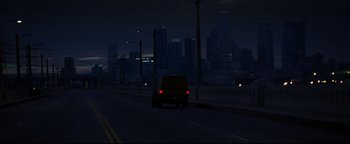 Movie still from “Terminator 3: Rise of the Machines” (2003), directed by Jonathan Mostow – A car driving down a street at night with a city skyline in the background; Extreme Wide shot, High angle