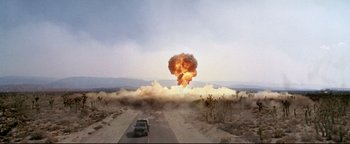 Movie still from “Terminator 3: Rise of the Machines” (2003), directed by Jonathan Mostow – A car driving down a road with a bomb exploding in the background; Extreme Wide shot, Low angle