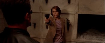 Movie still from “Terminator 3: Rise of the Machines” (2003), directed by Jonathan Mostow – A woman holding a gun in front of a brick wall; Medium shot, Over the shoulder angle