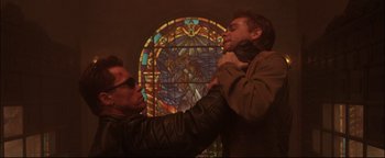 Movie still from “Terminator 3: Rise of the Machines” (2003), directed by Jonathan Mostow – Two men in front of a stained - glass window; Close Up shot, Low angle