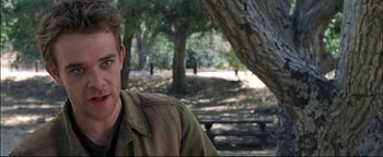 Movie still from “Terminator 3: Rise of the Machines” (2003), directed by Jonathan Mostow – A man sitting in the shade of a tree; Close Up shot, Over the shoulder angle