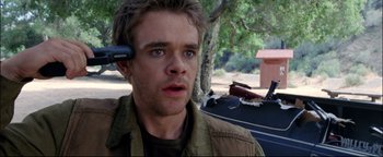 Movie still from “Terminator 3: Rise of the Machines” (2003), directed by Jonathan Mostow – A person with a cell phone on his head; Close Up shot, Over the shoulder angle