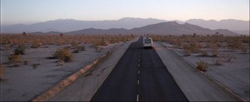 Movie still from “Terminator 3: Rise of the Machines” (2003), directed by Jonathan Mostow – An rv traveling down a road in the middle of the desert; Extreme Wide shot, High angle