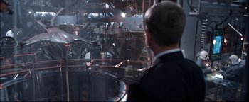 Movie still from “Terminator 3: Rise of the Machines” (2003), directed by Jonathan Mostow – A man in a suit looking out a window; Extreme Wide shot, Over the shoulder angle