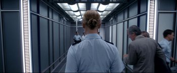 Movie still from “Terminator 3: Rise of the Machines” (2003), directed by Jonathan Mostow – A woman in a uniform walking down a hallway; Medium shot, Over the shoulder angle