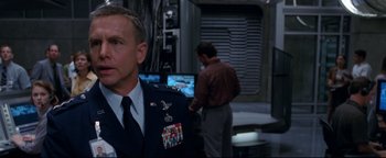 Movie still from “Terminator 3: Rise of the Machines” (2003), directed by Jonathan Mostow – A man in a military uniform standing in front of two other men; Medium shot, Over the shoulder angle