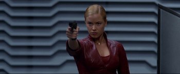 Movie still from “Terminator 3: Rise of the Machines” (2003), directed by Jonathan Mostow – A woman holding a gun while standing in front of a wall; Close Up shot, Over the shoulder angle