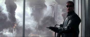Movie still from “Terminator 3: Rise of the Machines” (2003), directed by Jonathan Mostow – Smoke billows from a building in the background; Medium shot, Low angle