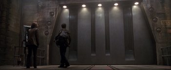 Movie still from “Terminator 3: Rise of the Machines” (2003), directed by Jonathan Mostow – A man with a back pack walking up a flight of stairs; Wide shot, Low angle