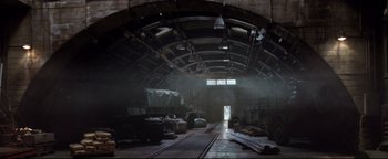 Movie still from “Terminator 3: Rise of the Machines” (2003), directed by Jonathan Mostow – An old train station with cars parked on the tracks; Extreme Wide shot, High angle