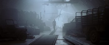 Movie still from “Terminator 3: Rise of the Machines” (2003), directed by Jonathan Mostow – A man is walking through a warehouse in the fog; Extreme Wide shot, Low angle