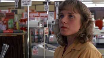 Movie still from “Terms of Endearment” (1983), directed by James L. Brooks – A woman standing in front of a store with many signs; Close Up shot, Low angle