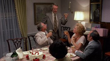 Movie still from “Terms of Endearment” (1983), directed by James L. Brooks – A group of people sitting around a table with cake; Medium shot, High angle