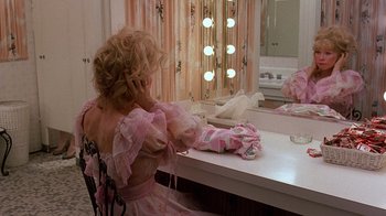 Movie still from “Terms of Endearment” (1983), directed by James L. Brooks – A woman sitting at a table in front of a mirror talking on a cell phone; Medium shot, Over the shoulder angle